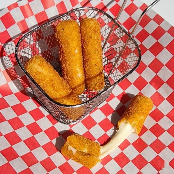 Golden fried mozzarella sticks in a metal basket and one pulled apart with melted cheese.